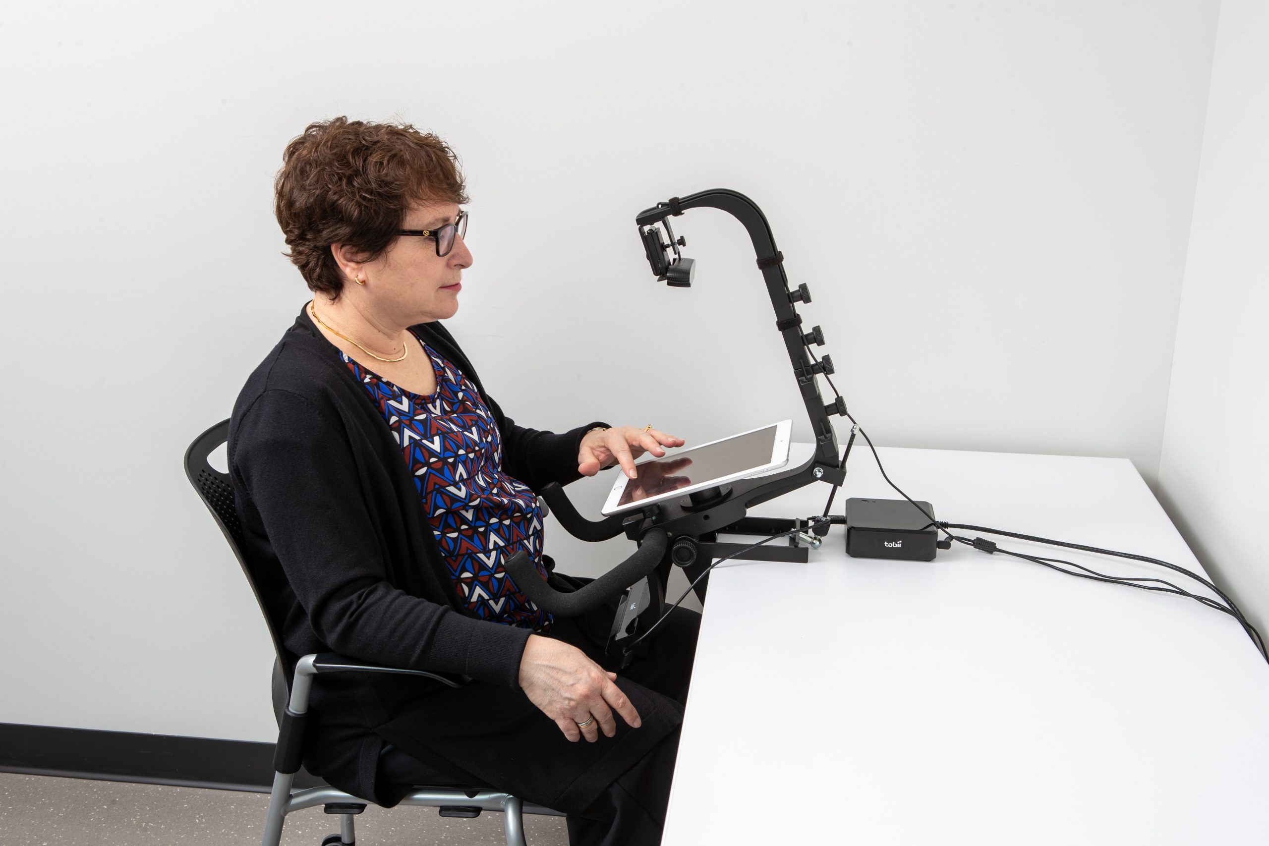 Photo of a woman sitting at a desk using a tablet on a stand