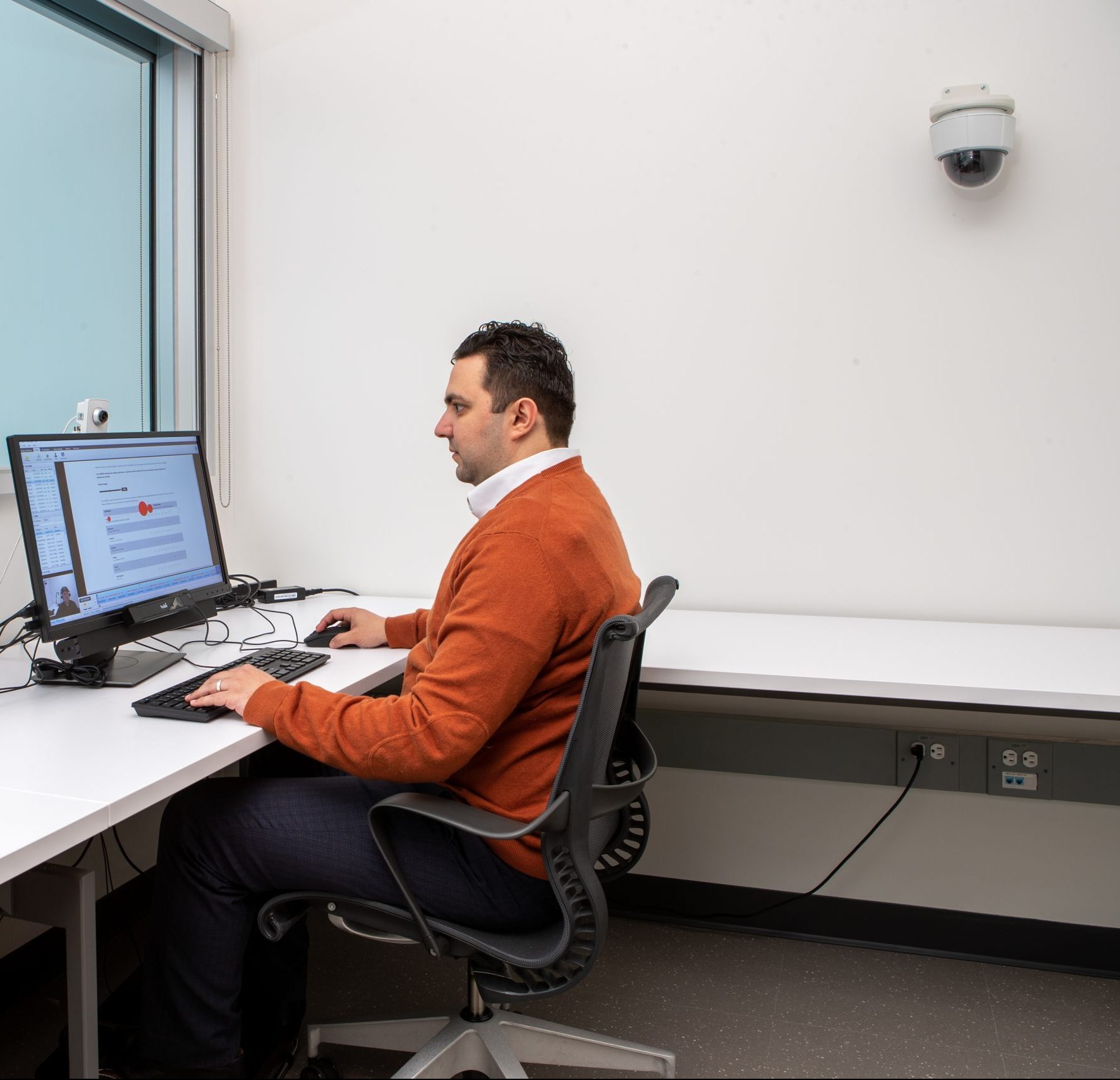 Photo of a man sitting at a desk on a computer in a lab space